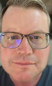 White man wearing glasses wearing a blue shirt